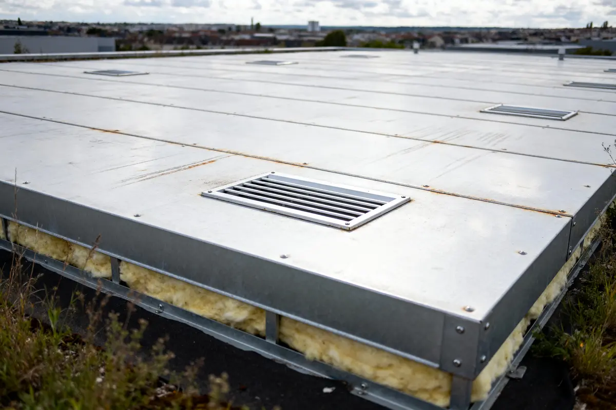 Toit plat en bac acier avec grilles de ventilation et isolation apparente