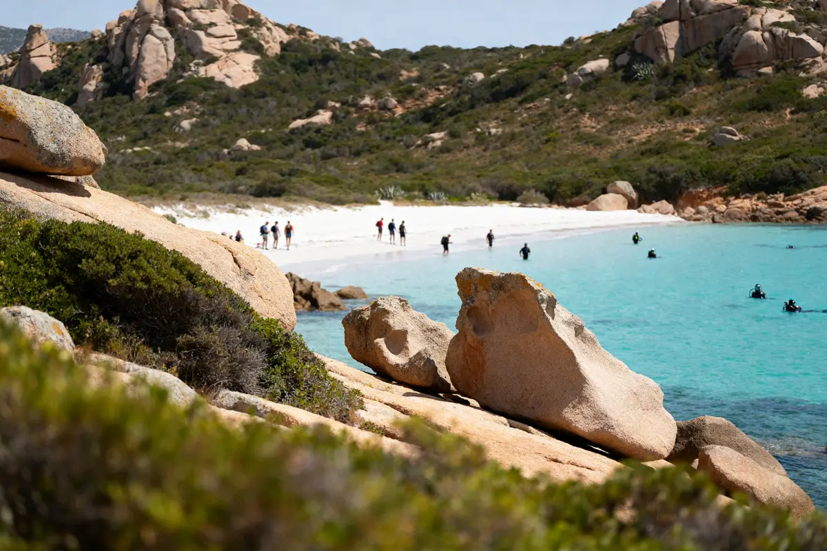 Plage de sable blanc avec plongeurs dans l'eau turquoise à La Maddalena en Italie
