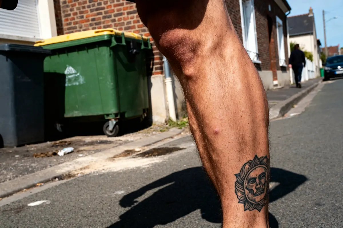 Tatouage au mollet d'un homme avec dessin de soleil sur fond urbain